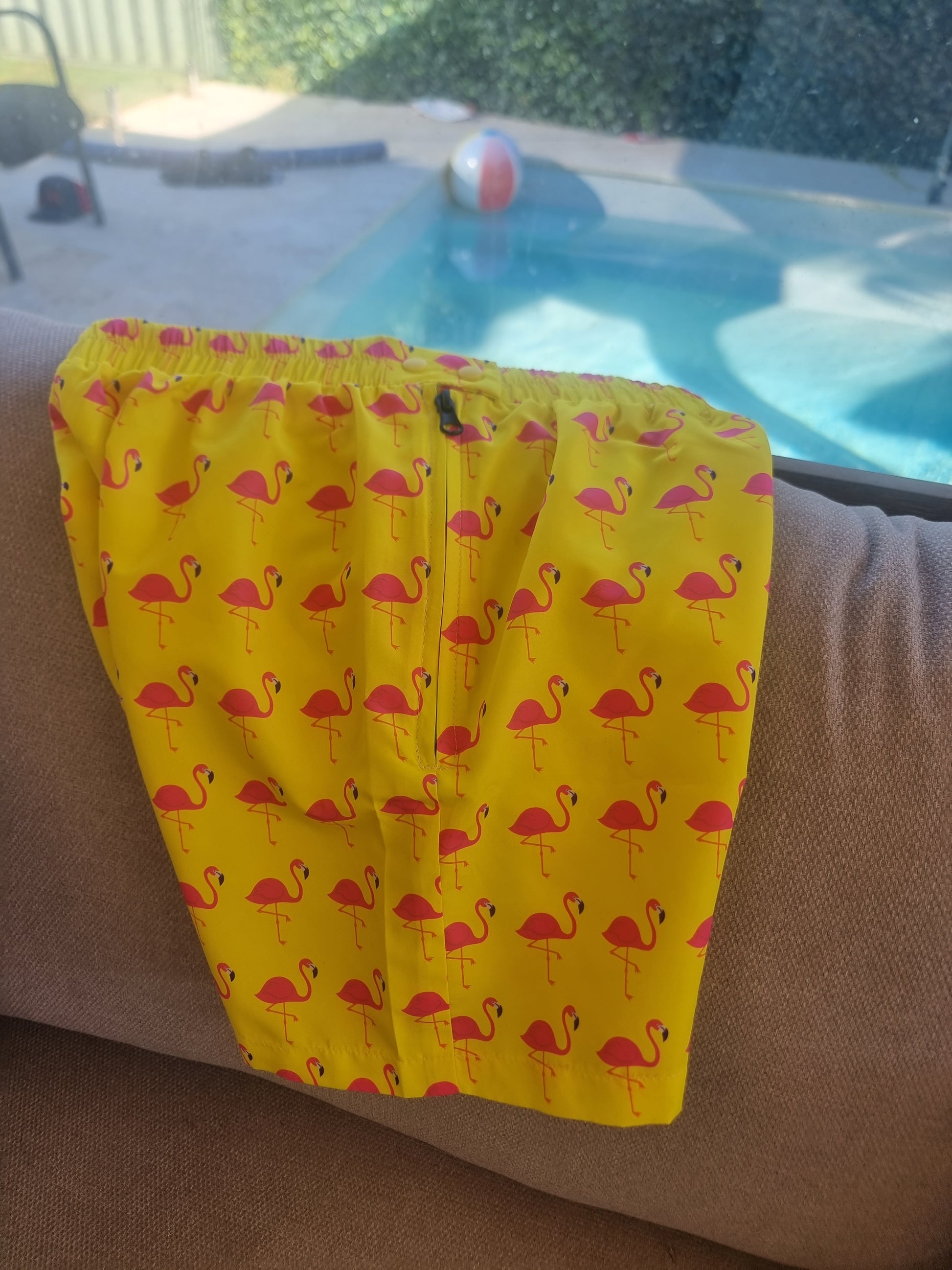 Fluoro safety yellow boardshorts with pink flamingo design, featuring colorful pop buttons and an easy side zip.